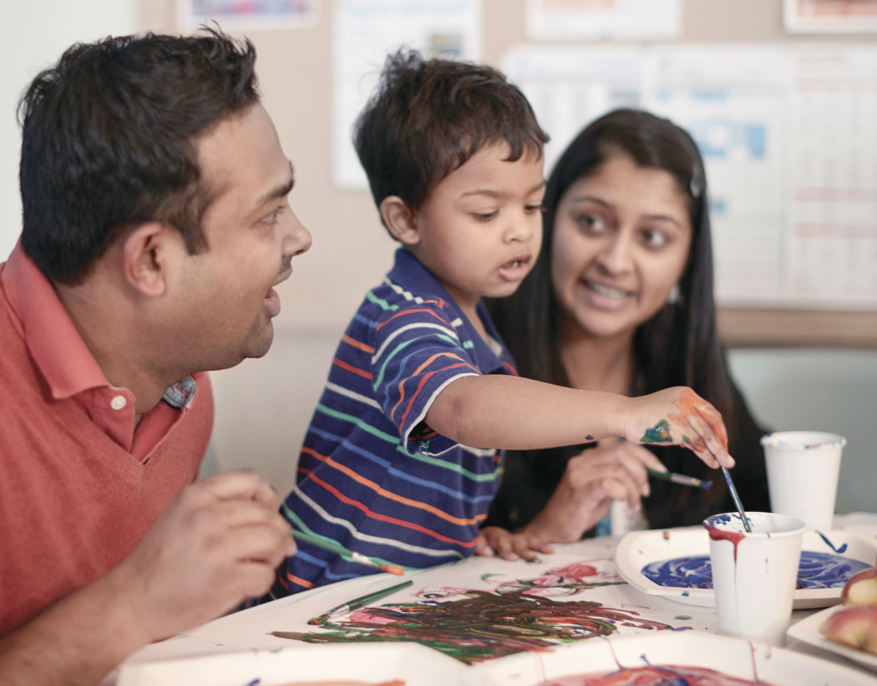 preschool boy painting with parents