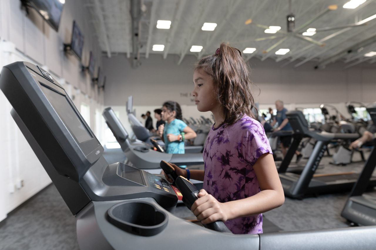 A pre-teen girl begins her workout on a treadmill
