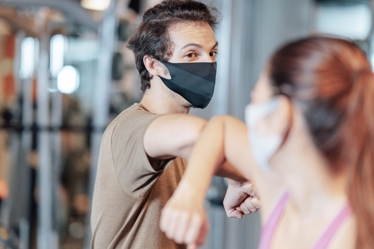 Masked man and woman touch elbows