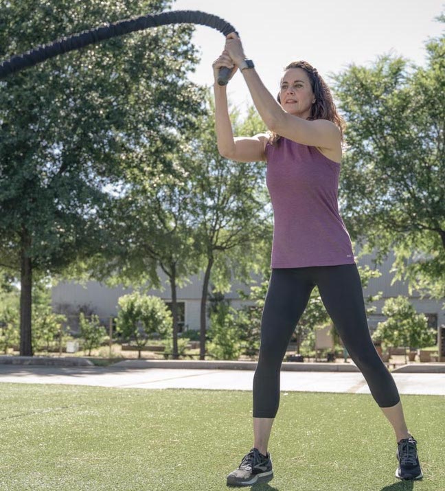 A woman using battle ropes outside