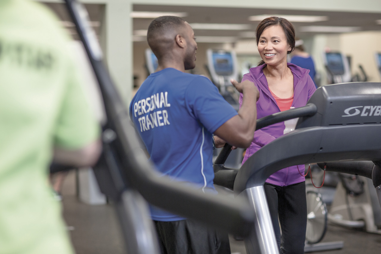 A personal trainer coaches a woman on a treadmill